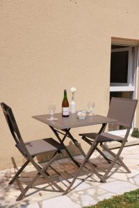 a picnic table with two chairs and a bottle of wine at Pierre de Lune in Bayeux