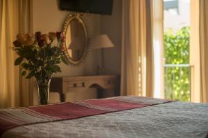 Un dormitorio con una cama con un jarrón de flores y un espejo en Villa Mirasol, en San Miguel de Allende