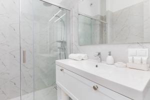 La salle de bains blanche est pourvue d'un lavabo et d'une douche. dans l'établissement Stylish & Trendy Apartment Browar Gdański by Renters, à Gdańsk
