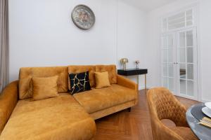 - un canapé brun dans le salon avec une horloge murale dans l'établissement Stylish & Trendy Apartment Browar Gdański by Renters, à Gdańsk