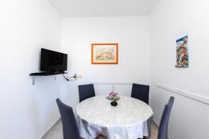 a white table with chairs and a tv on a wall at Apartment Miljenko in Lopar