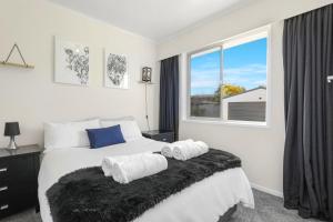 a white bedroom with a large bed with towels on it at Sunny Inn Tawavale in Rotorua