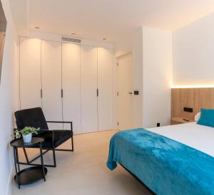 een slaapkamer met een bed en een stoel bij RD Hotel Apartamento in Poio