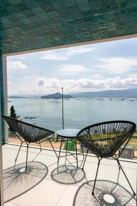 twee stoelen en een tafel op een balkon met uitzicht op het water bij RD Hotel Apartamento in Poio