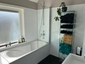 a bathroom with a tub and a glass shower at BeBaBops Homestay Utrecht in Utrecht