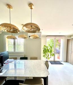 Habitación con mesa con sillas y lámparas de araña. en Espace Les Orangers - Piscine - 10mn plages, en Six-Fours-les-Plages