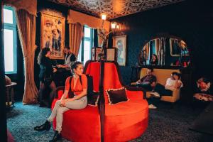 Pensão Amor Madam's Lodge في لشبونة: امرأة تجلس على كرسي احمر في غرفة
