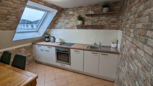 a kitchen with white cabinets and a brick wall at Familien Apartments in bester Lage in Butjadingen