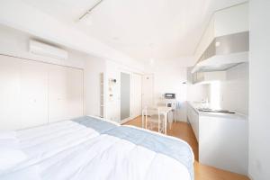 a white bedroom with a large bed and a kitchen at Granduo 松濤 in Tokyo
