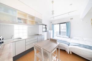 a white kitchen with a bed and a table at Granduo 松濤 in Tokyo