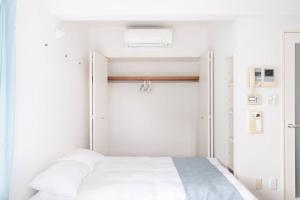 - une chambre avec un lit blanc et un placard dans l'établissement Granduo 松濤, à Tokyo