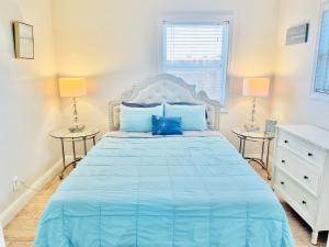 een slaapkamer met een groot blauw bed en 2 tafels bij Cozy Beach Cottage with Bicycles in San Diego