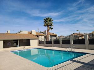 a swimming pool in front of a house with a palm tree at 2bed 1 bath condo near Nellis afb & the strip in Las Vegas