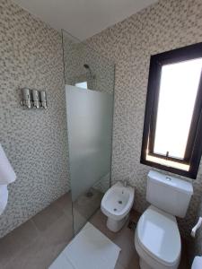 a bathroom with a toilet and a sink and a window at Hada del Champaqui - Posada de Montaña in Villa General Belgrano
