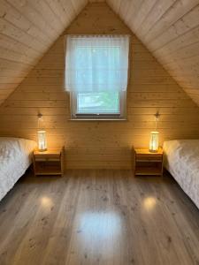 a attic room with two beds and a window at Domki nad jeziorem Łąkowa in Gietrzwałd