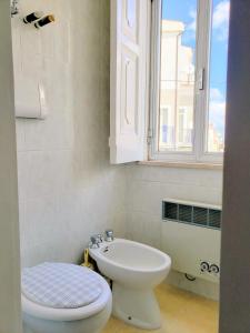 un bagno con un water, un lavandino e una finestra di Dimora Maggi al Corso - Affitti Brevi Italia a Monte SantʼAngelo