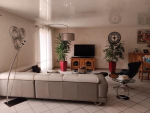 uma sala de estar com um sofá branco e uma televisão em Villa spacieuse em Aussonne
