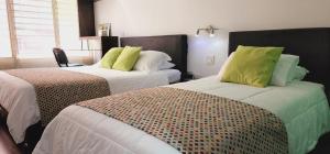 2 camas con almohadas verdes en una habitación en Hotel Austral Suites en Cali