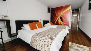 a bedroom with two beds and a painting on the wall at Hotel Austral Suites in Cali