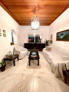 a living room with a white couch and a chandelier at Emerald Apartment in Spata