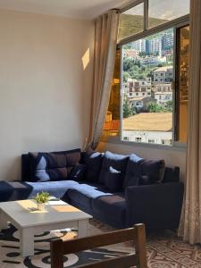 een woonkamer met een blauwe bank en een tafel bij Résidence Bejaia Legacy in Bejaïa