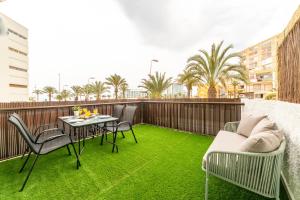 d'un balcon avec une table, des chaises et de l'herbe verte. dans l'établissement Trendy Homes Chumberas Seaview, à Roquetas de Mar