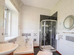 a bathroom with a shower and a tub and a sink at Old Distillery in Halkirk