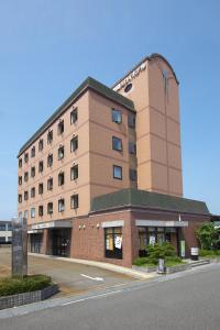 a large brick building with a road in front of it at Toyooka Sky Hotel in Toyooka