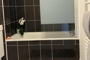a bathroom with a bath tub with a vase of flowers at Élégance et Confort entre Disney et Val d'Europe 6 Personnes+Parking in Serris