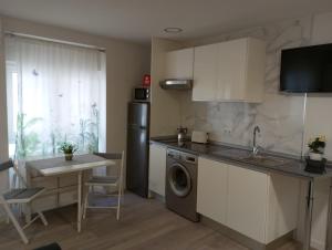 a kitchen with a sink and a dishwasher and a table at Apartamentos "El Balconico" in Arguedas