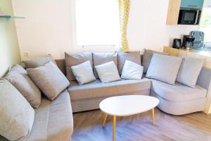 ein Wohnzimmer mit einem Sofa mit Kissen und einem Tisch in der Unterkunft Mobil-home 6/8 personnes - Camping Siblu **** Domaine de Dugny in Onzain