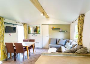 ein Wohnzimmer mit einem Sofa und einem Tisch in der Unterkunft Mobil-home 6/8 personnes - Camping Siblu **** Domaine de Dugny in Onzain