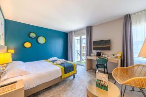 una camera da letto con una parete blu, un letto e una scrivania di Best Western Plus Hôtel Vannes Centre Ville a Vannes