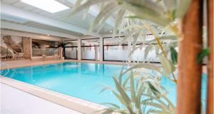 a large swimming pool in a hotel with a palm tree at Best Western Hotel Polisina in Ochsenfurt