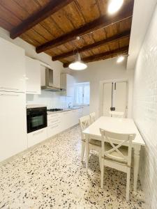 cocina blanca con mesa blanca y sillas en BLUE HOUSE - incantevole casa a due passi dal mare, en Grottammare