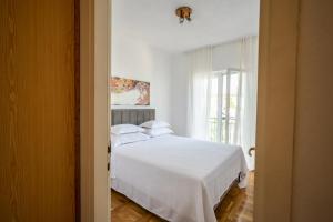 1 dormitorio con cama blanca y ventana en Apartment Mango, en Vinišće