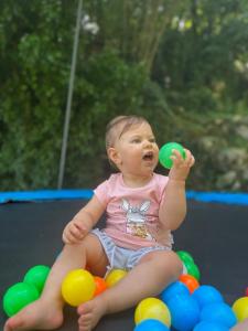 a baby sitting on a pile of balls holding a ball at Auto camp Radoman in Virpazar