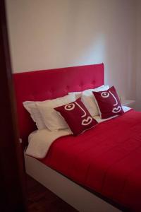 a red bed with red sheets and pillows on it at Central Apartment in Belas, Lisbon in Belas