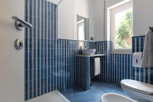 W wyłożonej niebieskimi kafelkami łazience znajduje się umywalka i toaleta. w obiekcie B&B Sapore di Mare nel Blu w mieście Gaeta