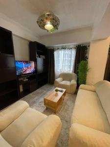 a living room with two white couches and a tv at Stylish and Cozy 3BR in the Heart of BGC in Manila