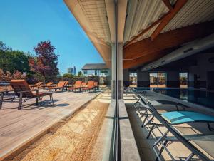 - une terrasse avec des chaises et une piscine dans un bâtiment dans l'établissement Golden Tulip Dieppe Hôtel & Spa, à Saint-Aubin-sur-Scie
