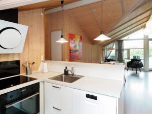 una cocina con armarios blancos y fregadero en Four-Bedroom Holiday home in Slagelse 2, en Store Kongsmark