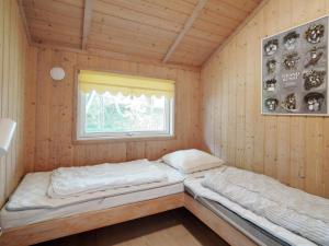 two beds in a wooden room with a window at Four-Bedroom Holiday home in Slagelse 2 in Store Kongsmark