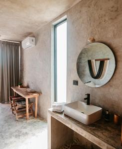 a bathroom with a sink and a mirror on the wall at DOS MARES Pool Club Boutique Hotel in El Cuyo
