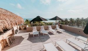 a deck with chairs and umbrellas on a resort at Dos Mares Barefoot Luxury in El Cuyo
