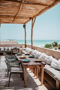 uma mesa de madeira e cadeiras num pátio com o oceano em DOS MARES Pool Club Boutique Hotel em El Cuyo