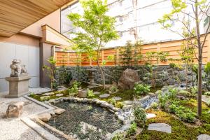 a garden in front of a building with a fountain at Ryokan Ginkaku Kyoto in Kyoto