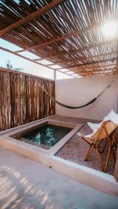 a pool of water with a hammock and a chair at DOS MARES Pool Club Boutique Hotel in El Cuyo