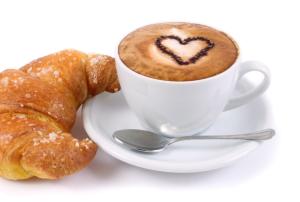 een kop koffie en een croissant op een bord bij b&b Poseidone in Alassio