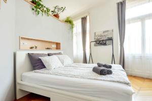a white bedroom with a bed with two pillows on it at Dohany Design Apartments in Budapest
